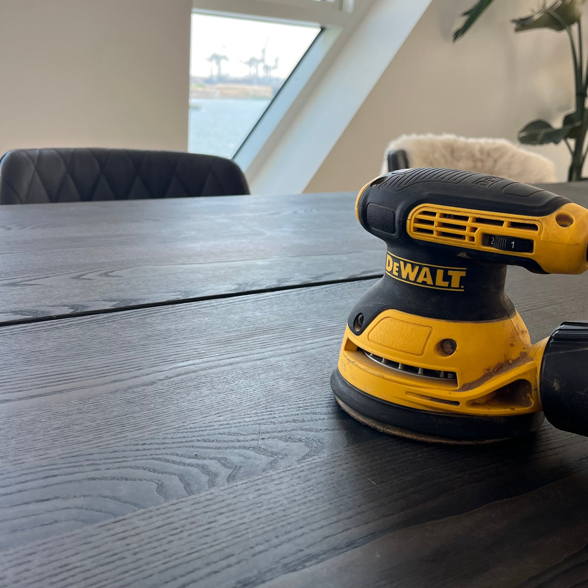 Dewalt excentersliber i gang med at slibe køkkenbord i Isbjerget på Aarhus Ø – nænsom og præcis slibning af træoverflade som forberedelse til efterbehandling.
