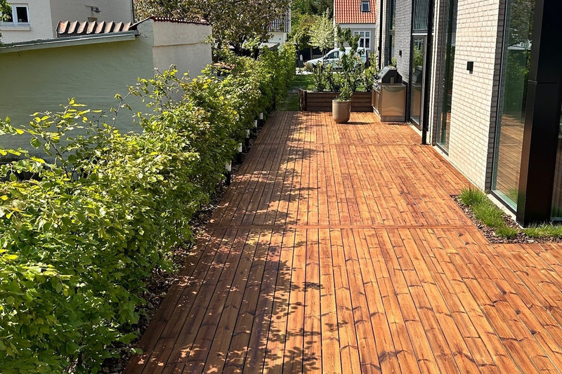 Langt terrasseforløb i behandlet træ langs moderne villa
